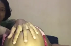 Mulher com pele morena alternando entre usar os dedos e um brinquedinho no bundão guloso